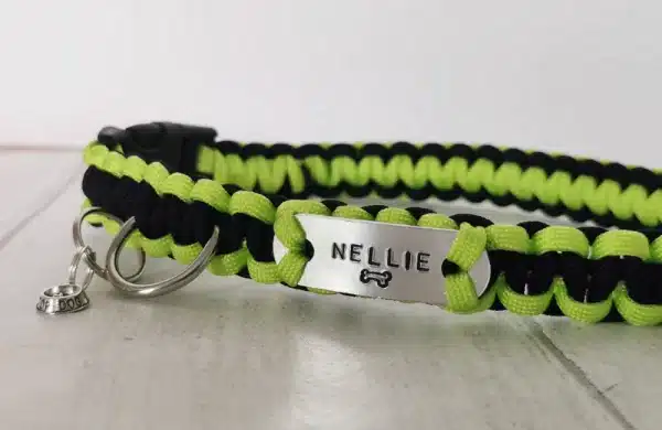 A handmade dog collar braided with high viz yellow paracord 550 in the cobra knot style with a metal name tag displaying the dogs name 'NELLIE'